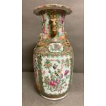 A Famille rose baluster vase painted in the canton style with figural scenes and moulded foo dog