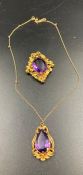 A stylish brooch and pendant both with central purple stones and the pendant is on a 9ct gold