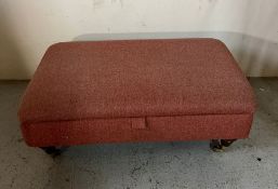 An upholstered foot stool opening to storage
