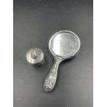A silver pill box and small handheld mirror.