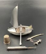 A small selection of silver curios to include a boat, button hook, thimble and decorative sword.