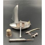 A small selection of silver curios to include a boat, button hook, thimble and decorative sword.