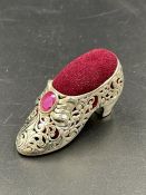 A silver plated pin cushion in the form of a shoe set with a ruby.