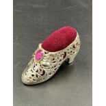 A silver plated pin cushion in the form of a shoe set with a ruby.