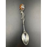 A silver caddy spoon of Art Nouveau form with an amber top.