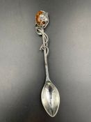 A silver caddy spoon of Art Nouveau form with an amber top.