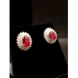18ct yellow gold oval cut ruby earrings surrounded by double row of brilliant cut diamonds,