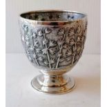 An Oriental silver cup on a raised foot with foliate decoration, stamped for Grish Chunderdutt