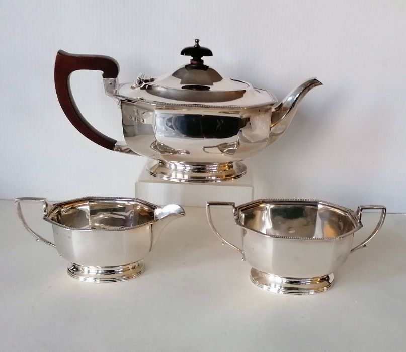 An Art Deco silver three-piece tea service of faceted design with gadronned edges on raised bases, t