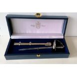 A miniature ceremonial sword/letter opener by Pooley, London, with metal scabbard, in fitted case