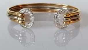 A gold bi-colour cuff bangle with diamond decoration, stamped and tests for 18ct, 23.6g