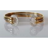 A gold bi-colour cuff bangle with diamond decoration, stamped and tests for 18ct, 23.6g