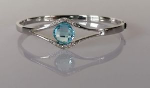 A white gold bangle with split shank enclosing a blue topaz, 12.80 carats, and diamond decoration, C
