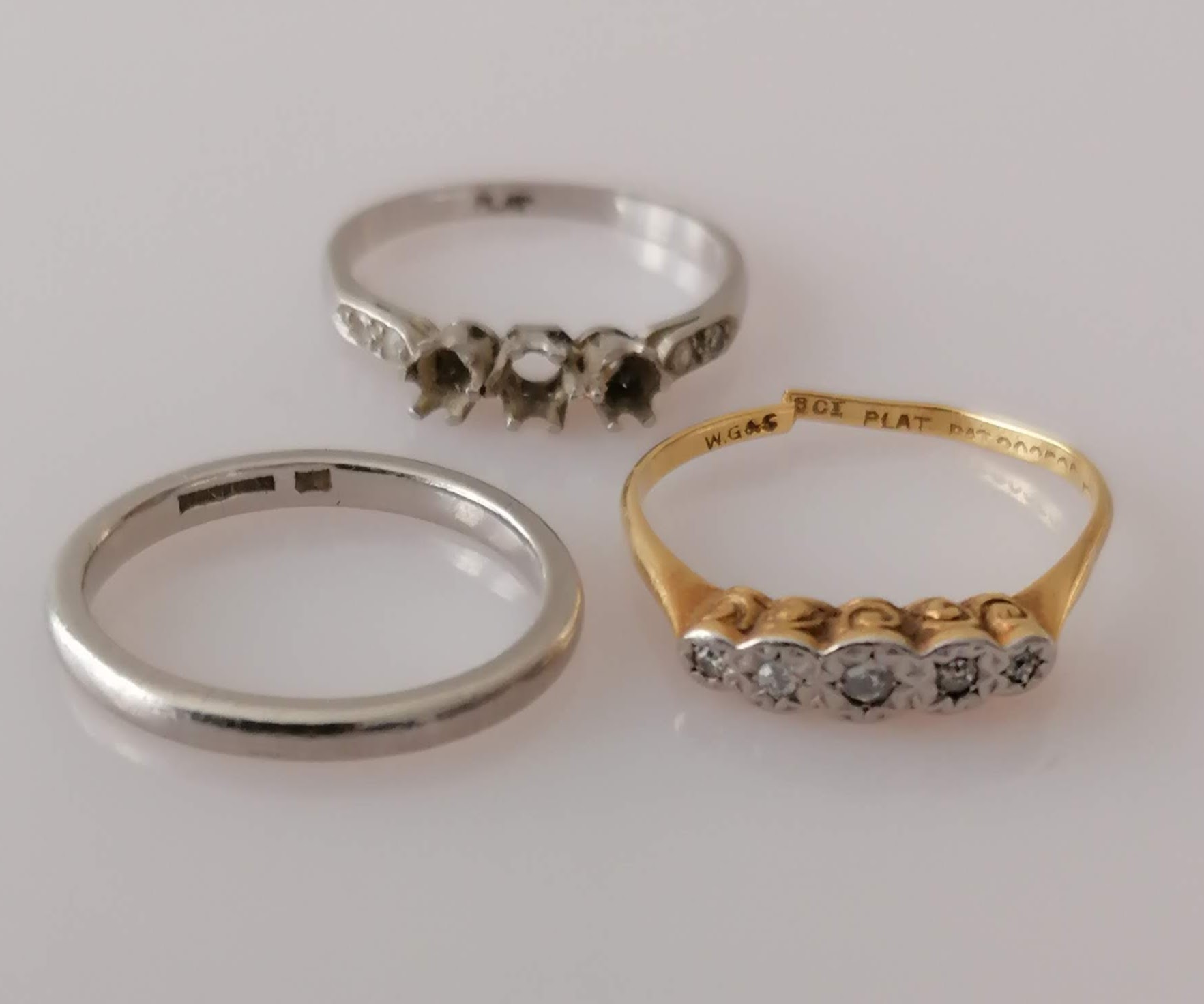 A platinum wedding band, a platinum ring without stones, sizes N, P and an 18ct yellow gold and