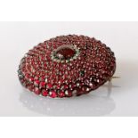 A Victorian circular convex garnet and seed pearl brooch on a base metal back, 35mm