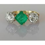 A three-stone emerald and diamond ring, the central square step-cut emerald approximately 6.60 x 6.