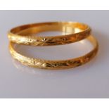 A pair of gold bangles with etched floral decoration, stamped and testing for 22ct, internal