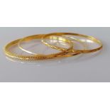 Three gold bangles, two with etched decoration, 60mm, 63mm x 2 diameter, unmarked but testing for
