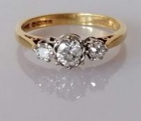 A three-stone diamond ring on an 18ct gold setting, the central diamond approximately 0.25 carats