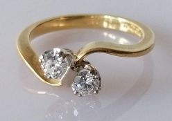 A two stone diamond crossover ring on a white double claw setting