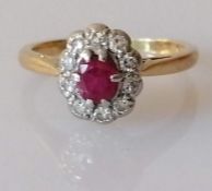 An ruby and diamond cluster ring on a yellow gold setting, the oval pinkish ruby, 5mm x 3mm