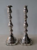 A pair of George V silver candlesticks of bobbin baluster form with embossed rococo decoration