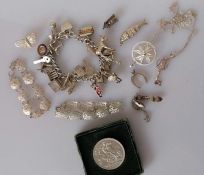 A silver charm bracelet, a 1951 silver crown and an assortment of other silver based jewellery, 145g