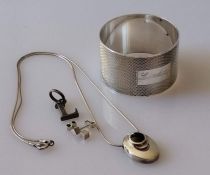 A silver napkin ring with engine-turned design, inscribed; a silver pendant and chain, silver pendan