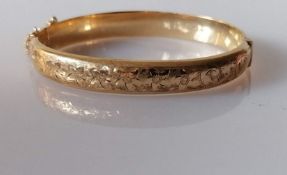 A 9ct yellow gold hinged bangle with floral etched decoration, hallmarked, 12.37g