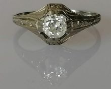An Art deco-style solitaire diamond ring on a raised setting, the round-cut diamond
