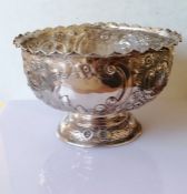 A late Victorian silver rose bowl with pie crust border, profusely embossed rococo decoration on a s