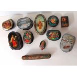 An assortment of ten Russian lacquered trinket boxes and a brooch from various traditions