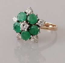 An emerald and diamond flower ring on white and yellow metal