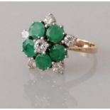 An emerald and diamond flower ring on white and yellow metal