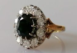 An oval dark green sapphire and diamond cluster ring on an 18ct yellow gold setting