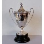 A George V silver two-handled trophy cup and cover the the neo-classical style on a turned ebonised