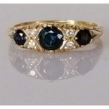 A graduated three-stone sapphire and diamond ring on a carved 18ct yellow gold setting