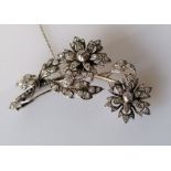 An Art Deco diamond spray brooch comprising a two-branch sprig with leaves and flowers