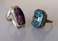 Two silver set rings, one a large aqua-coloured stone with marcasite border, the other a purple ston