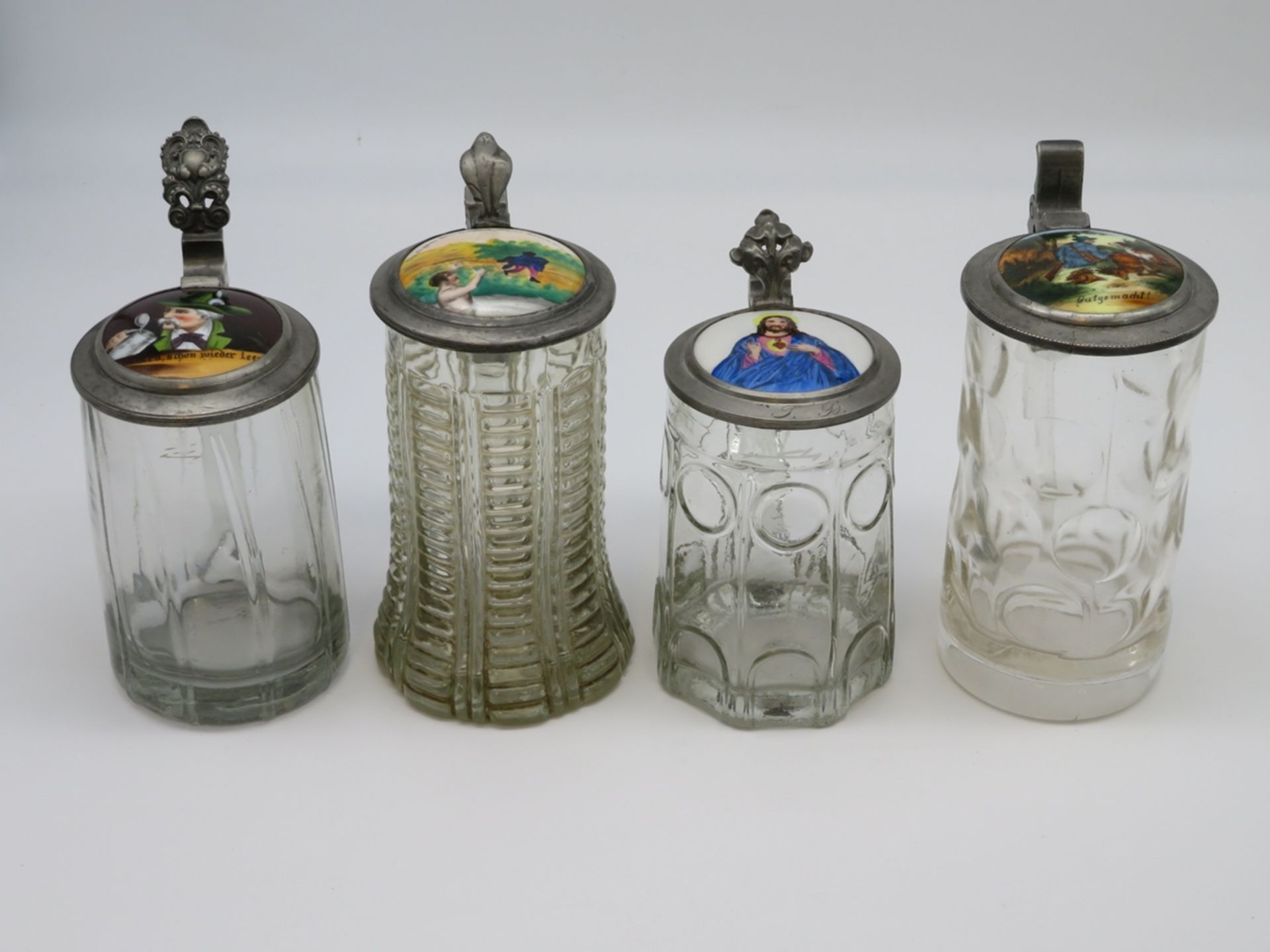 4 diverse Bierkrüge, 19. Jahrhundert, farbloses Glas, bemalte Porzellandeckel in Zinnmontur, ca. h 