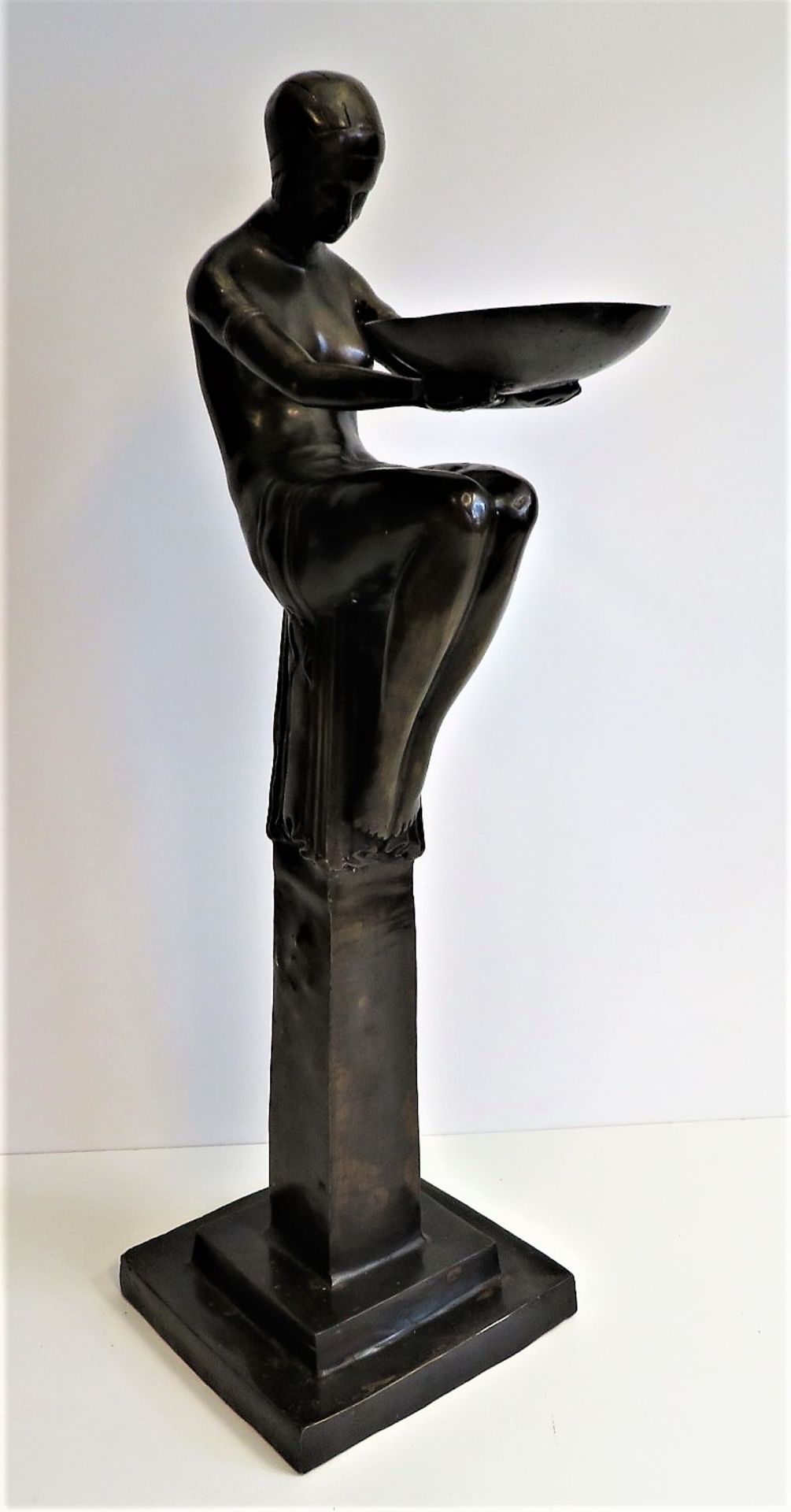 Unbekannt, Auf Säule sitzende Art-Déco-Figur mit Schale, Messing patiniert, 81 x 23 x 23 cm.