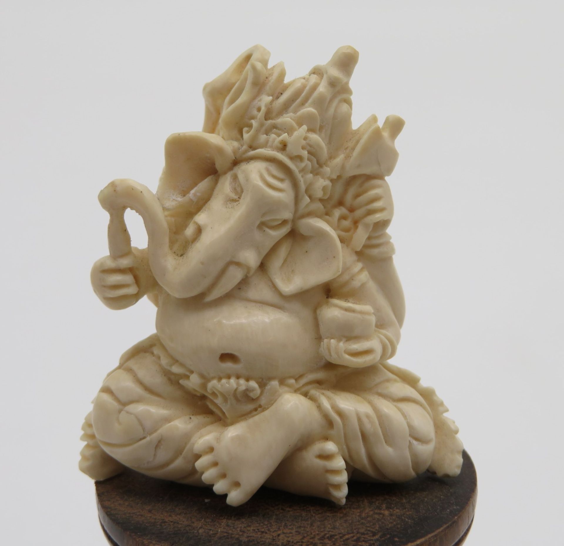Sitzender Elefantengott Ganesha mit diversen Attributen, Bein feinst geschnitzt, Holzsockel (h 3,5 