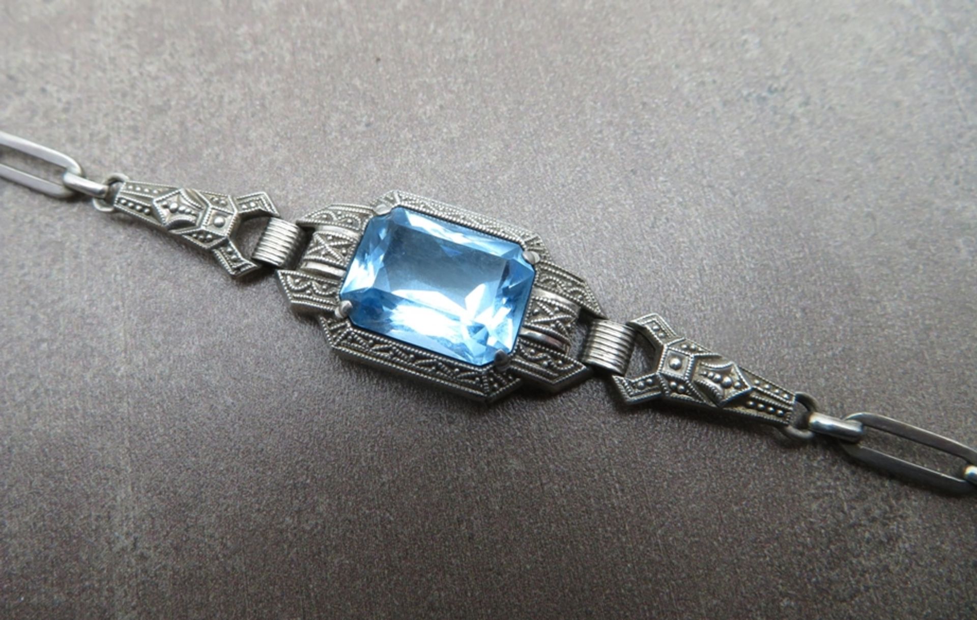 Elegantes Art Déco Armband, um 1910, mittig facettierter Blautopas, geometrisch modellierte Fassung