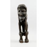 Kunsthandwerk - Afrika - Statue eines Hockenden. - Holz, schwarz gefärbt.