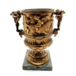Antique gilt bronze urn with putti decoration on a marble base 25cm high. Has a fault to the base of