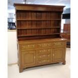 An Antique oak dresser with three tier delft rack, the base having 6 short drawers and 2