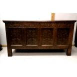 Antique oak 4 panel coffer, with heavy carved decoration, split to top, on square block legs, 153 cm