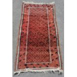 Balouch Persian rug c1920s in red. Measures 210 x 105cm. In used condition with slight a/f to side.