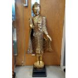 Hand carved wooden standing Buddha figure with gilded decoration and coloured glass detail on an