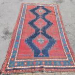 Persian red ground rug with blue geometric central medallions, some repair and ,wear, 145 cm wide,